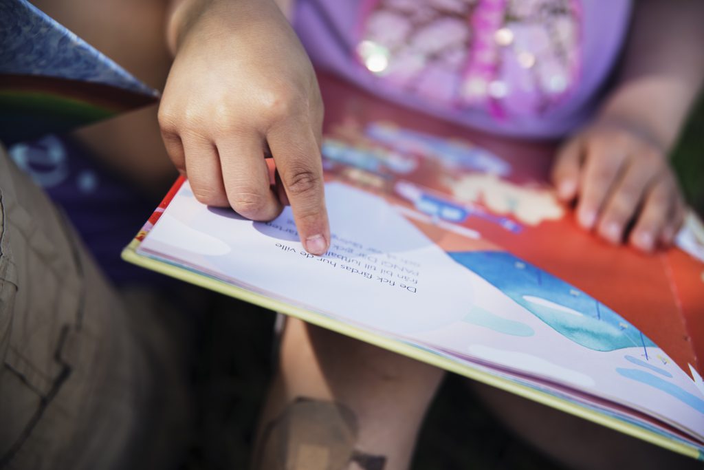 En barnhand som pekar på bokstäverna i en bilderbok